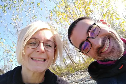 Dvoje nasmejanih ljudi na jesenjem izletu